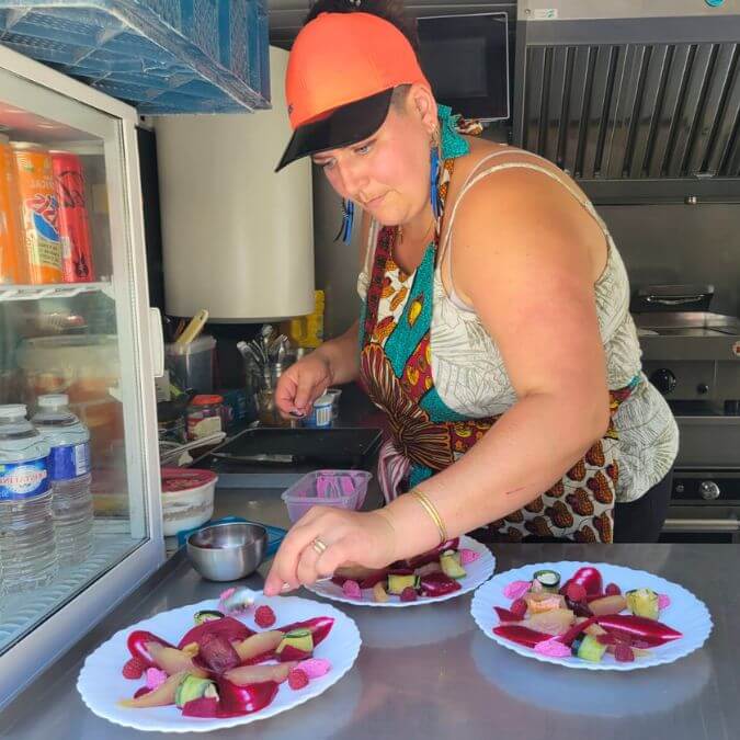 Florence concentrée en train de dresser des assiettes colorées dans le camion