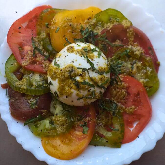 Assiette de tomates anciennes et burrata au pesto.